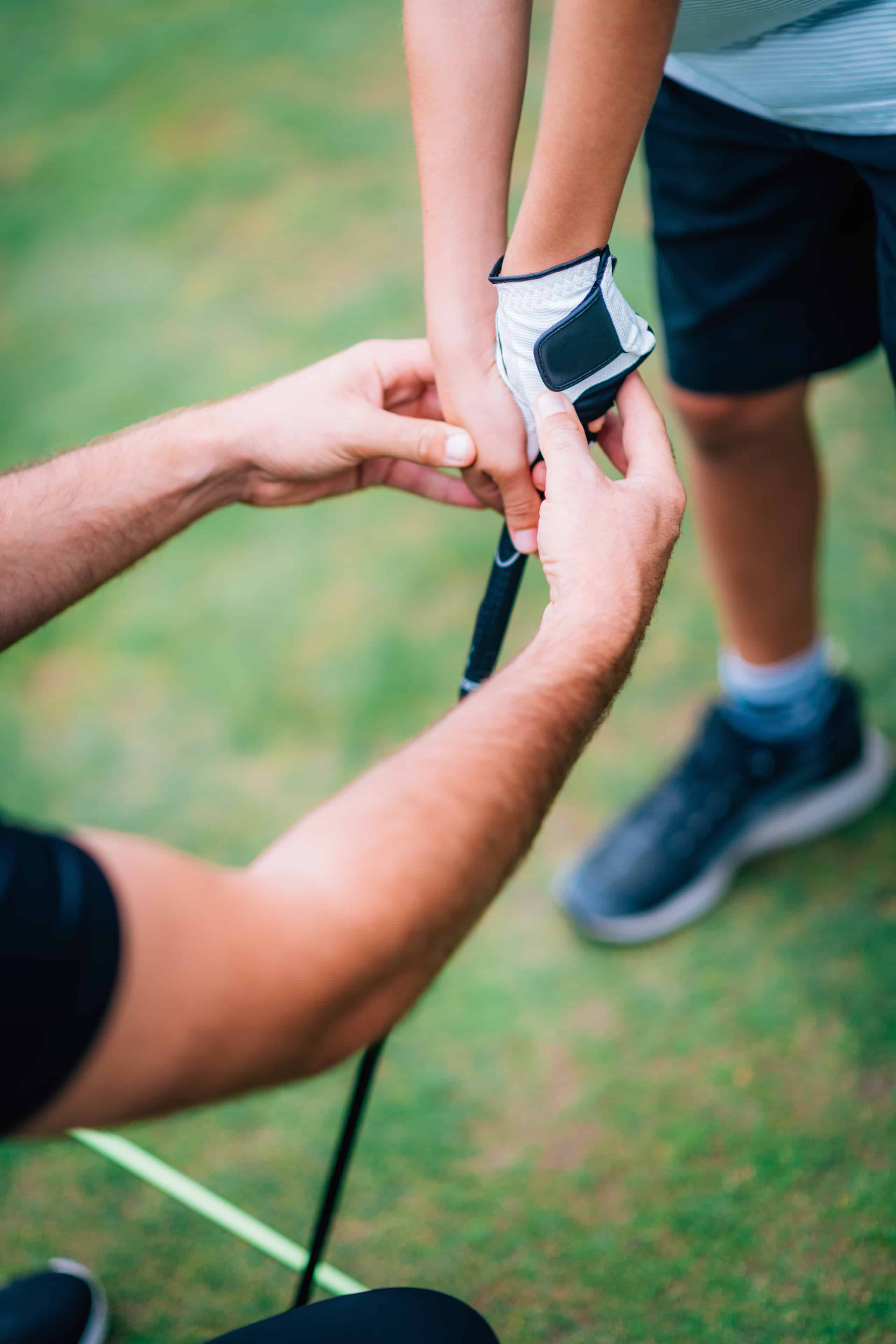golf-instructor-adjusting-young-boys-grip